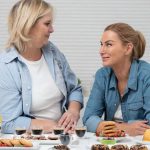 Two women sharing desserts and coffee at a table, smiling and enjoying each other's company.